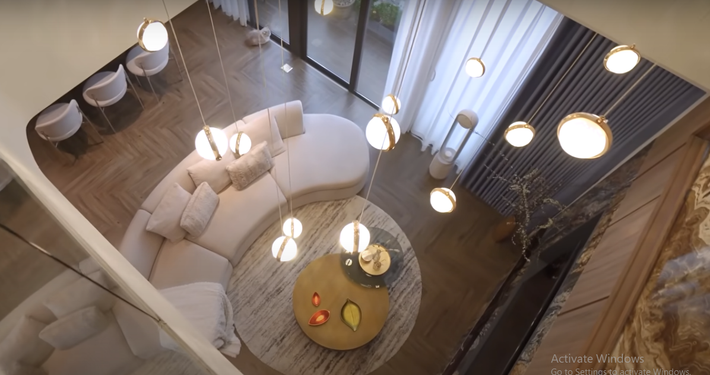 Căn hộ có diện tích mặt sàn 90m2, 2 tầng là 180m2. Phòng khách nổi bật với bộ sofa cong mềm mại.