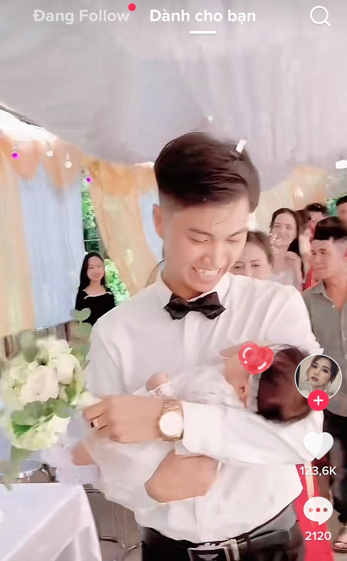 Cụ thể trong đoạn clip, chú rể ân cần bế một em bé khoảng vài tháng tuổi tiến vào lễ cưới. Gương mặt anh tràn ngập niềm hạnh phúc, em bé cũng nằm rất ngoan ngoãn trong lòng.