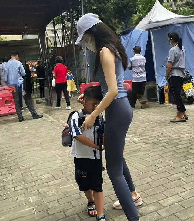 Cụ thể, người mẹ khi đến đón con ở trường mặc bộ đồ tập gym mỏng tang, bó sát, khoe đôi chân dài nuột nà, tôn lên vóc dáng cân đối khiến cho tất cả mọi người từ bé tới lớn đi ngang qua đều phải liếc nhìn.