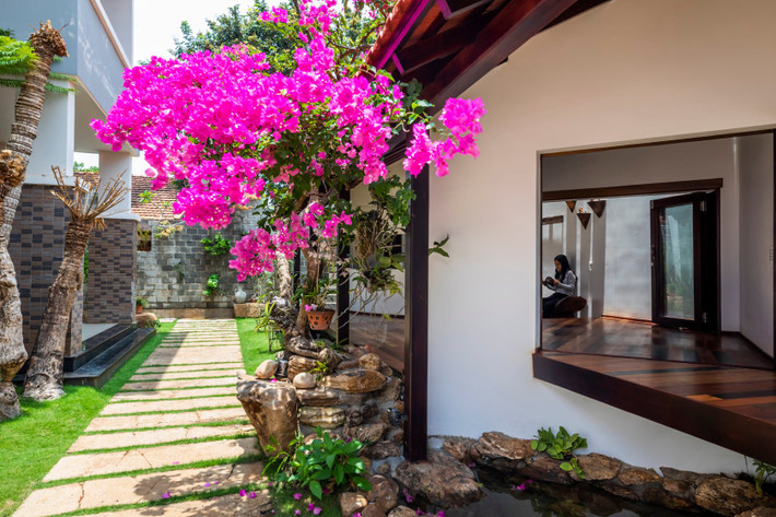 Hệ thống cây cối xanh mướt kết hợp cùng giàn hoa giấy và tiểu cảnh hồ nước giúp công trình thêm độc đáo. Ảnh: 6717 Studio