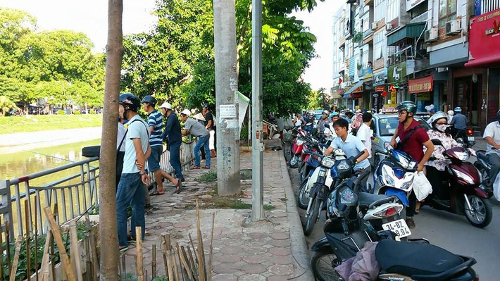 Rất nhiều người dân tụ tập hai bên bờ sông để xem câu cá. Đường Nguyễn Khang tắc một đoạn dài.
