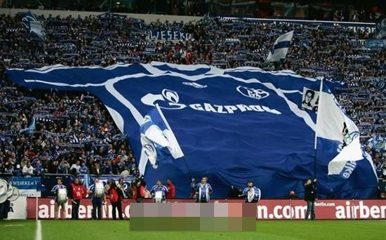 Các CĐV Schalke vào sân Veltins Arena mang chiếc áo khổng lồ của đội bóng lên khán đài để cổ vũ đội nhà.