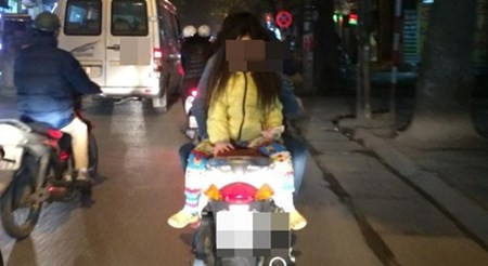 Hình ảnh bà mẹ đèo con ngồi ngược, đầu không đội mũ bảo hiểm được chụp trên phố Hà Nội vào buổi tối.
