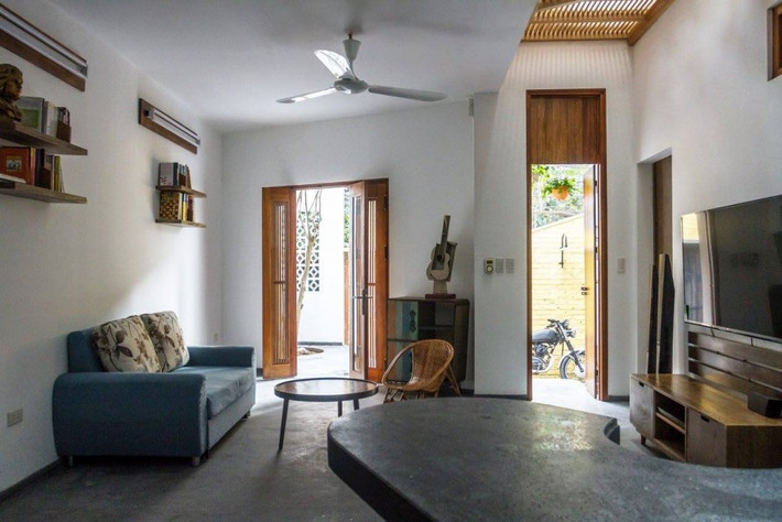 Phòng khách đơn giản gồm một sofa đơn, ghế mây và bàn trà nhỏ.