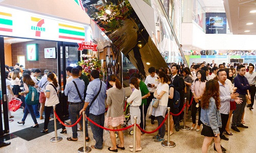 Cửa hàng 7-Eleven nằm trong tòa nhà Saigon Trade Center nơi tập trung nhiều văn phòng ở quận 1. Tranh thủ trước giờ làm việc, nhiều người xếp hàng mua sản phẩm ưu đãi tại cửa hàng mới khai trương.