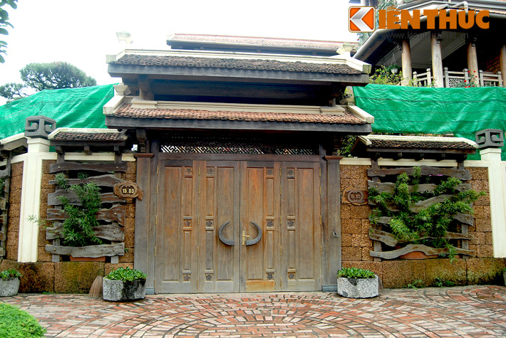 Chiếc cổng gỗ lớn, mái ngói và tay nắm cửa cách điệu sừng trâu tạo điểm nhấn lạ mắt cho biệt thự.