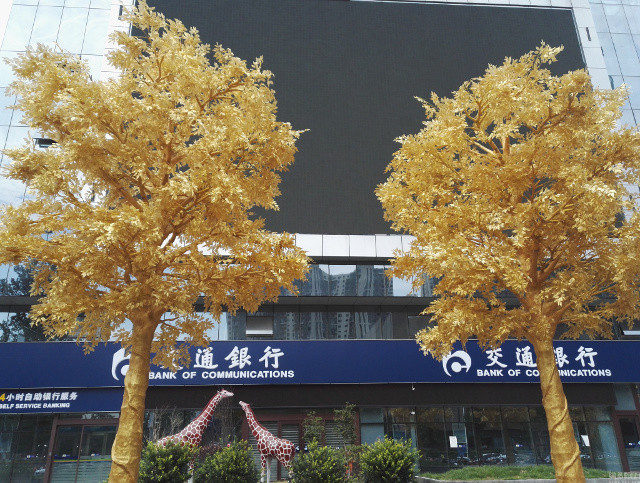 Một chi nhánh của ngân hàng Bank of Communications (BOCOM) tại thành phố Trịnh Châu, tỉnh Hà Nam, Trung Quốc khiến người dân ngỡ ngàng khi sử dụng vàng lá để quấn quanh 6 cây xanh ngay trước cổng chính. Ảnh: Shanghaiist.