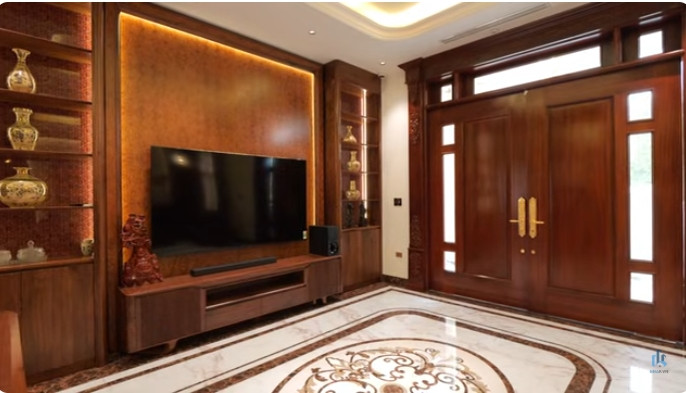 Bước qua cửa chính bằng gỗ lim bề thế là phần sảnh thiết kế liên thông với phòng khách. Ảnh chụp màn hình