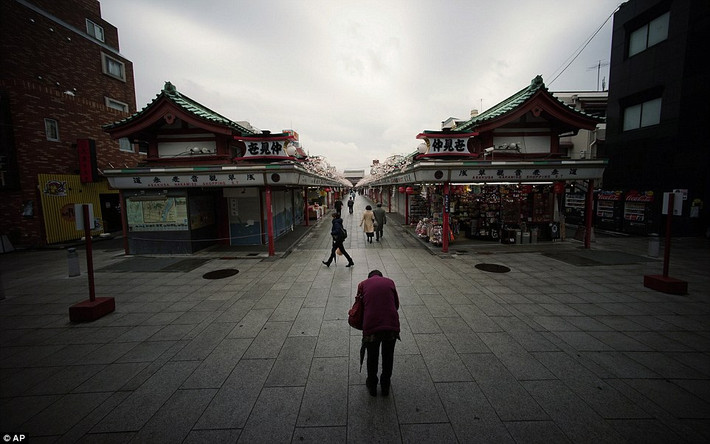 Cũng con phố Naakamise ngày nay ở quận Asakusa, Tokyo. Nơi đây vẫn là con phố mua sắm như ngày nào nhưng đã mang nhiều nét khang trang, hiện đại hơn. Trong hình là một du khách đang cầu nguyện hướng về phía ngôi đền Sensoji.