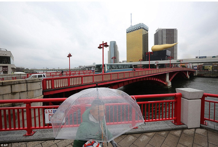 Vào lễ kỉ niệm 70 năm ngày Tokyo bị đánh bom, một người đàn ông đi bộ gần cây cầu trong khi đằng xa những tòa nhà hiện đại mọc lên tô điểm cho thành phố.