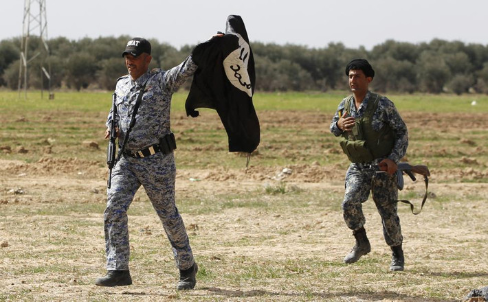 Một thành viên của lực lượng an ninh Iraq cầm lá cờ của Nhà nước Hồi giáo IS. Lá cờ này đã bị họ kéo xuống trước đó.