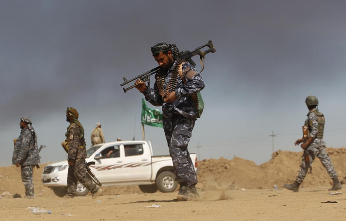 Một binh sĩ dòng Shi'ite đi bộ cùng khẩu súng vác trên vai ở thị trấn Tal Ksaiba, gần al-Alam, Iraq ngày 7/3/3015.