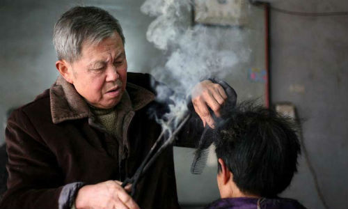 Ông Wang Weimei (trái ảnh) sử dụng chiếc kẹp để uốn tóc cho khách ở Miên Dương, tỉnh Tứ Xuyên phía tây nam Trung Quốc. Ông Wang,72 tuổi, vẫn giữ phương thức uốn tóc truyền thống với chiếc kẹp đặc biệt hàng thập kỷ. Phương thức này đã từng rất phổ biến ở Trung Quốc trước khi nó bị thay thế bởi công nghệ hiện đại vào những năm 1980.