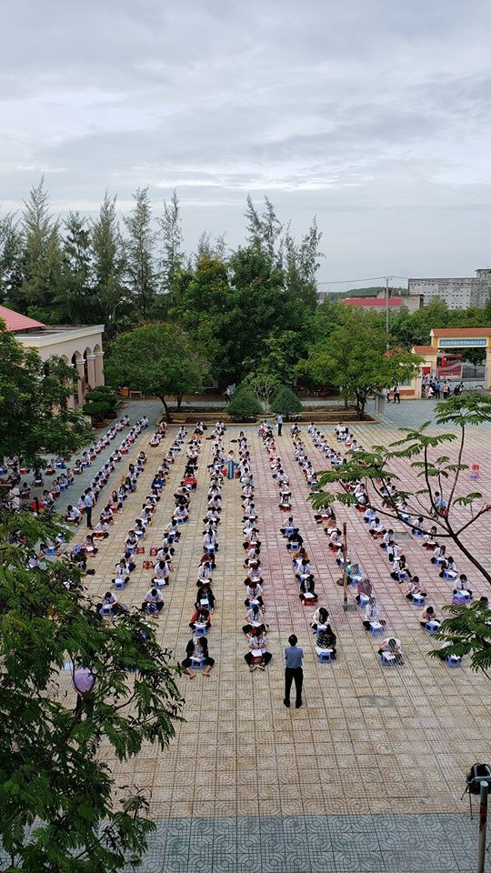 Theo như loạt ảnh chia sẻ trên MXH, các bạn học sinh ngồi bệt xuống đất, cách nhau mỗi người từ 1,5 đến 2 mét tạo thành các hàng dài ngồi dọc khắp sân để làm bài kiểm tra tập trung.