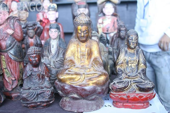 Các pho tượng Phật bằng gỗ với kích cỡ nhỏ được trưng bày bên cạnh các cổ vật khác tại gian hàng.