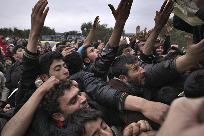 Chen chúc nhau nhận đồ cứu trợ tại trại tị nạn Atmeh, Syria, nơi trú ngụ hàng trăm nghìn người Syria mất nhà cửa trong chiến tranh.