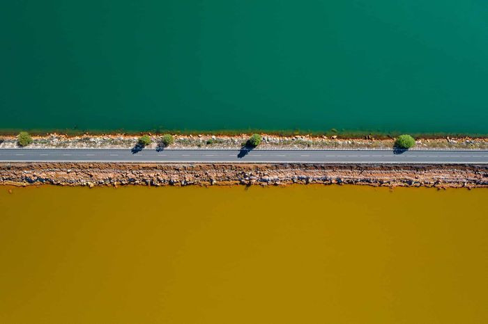 Bức ảnh này có tên "The Life: A narrow strip" chụp tải Huelva, Tây Ban Nha. Trong ảnh là con đường chia đôi hai hồ nước. Một bên là hồ nước sạch màu xanh, bên còn lại là nước ngả màu vàng vì bị ô nhiễm do khu khai thác mỏ của tập đoàn Rio Tinto. Ảnh: Roberto Bueno.