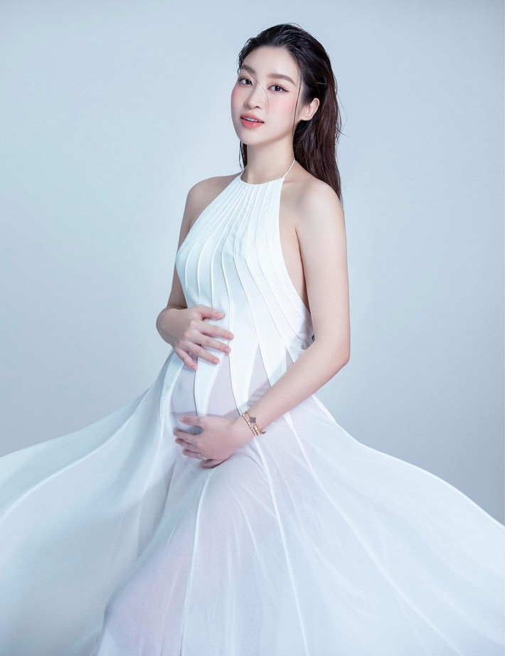 Đỗ Mỹ Linh sinh con đầu lòng hồi tháng 7. Hoa hậu Việt Nam 2016 chụp bộ ảnh kỷ niệm lần đầu làm mẹ với trang phục gợi cảm. Cô diện váy cổ yếm, khoét sâu hai bên mạn sườn. Chất liệu xuyên thấu, bay bổng của đuôi váy giúp người đẹp khoe bụng bầu (Ảnh: FBNV).