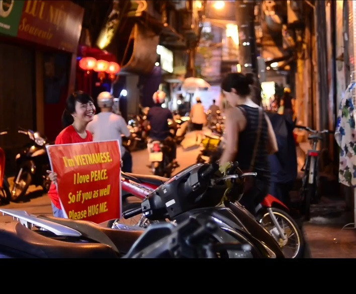 Cô bạn đi dạo trong khu phố cổ, gặp gỡ nhiều vị khách nước ngoài, cố gắng thể hiện suy nghĩ, tình cảm của mình qua tấm biển cầm trên tay...