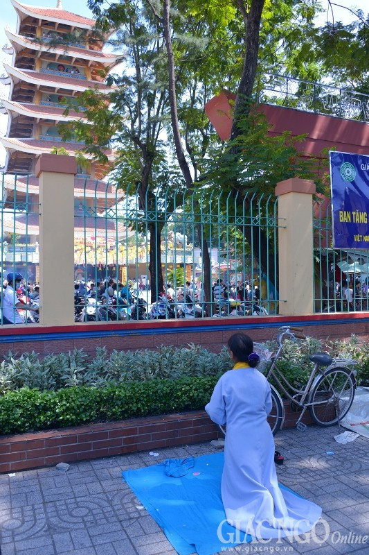 Còn đây, nữ Phật tử đã vọng cầu Tam bảo trong sự thành tâm bên ngoài cửa chùa khi bên trong dòng người mỗi lúc một đông - miễn là trong tâm có Phật thì tất nhiên thành tựu.