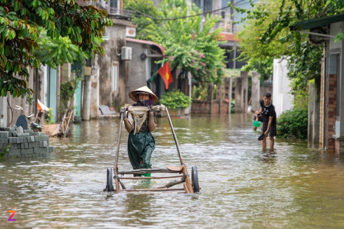 Bà Xuyến (người dân xóm Bến Vôi) tranh thủ lúc tạnh mưa dùng xe cải tiến đi lấy nước sinh hoạt về cho gia đình. "Tôi phải mặc thêm quần bảo hộ mới dám ra đường bởi nước ngập rất bẩn, nước giếng khoan cũng không đảm bảo vệ sinh để dùng ăn uống được", bà Xuyến nói.