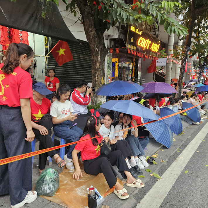 Người dân có mặt từ sớm, sử dụng ô, áo mưa, bạt để che mưa.