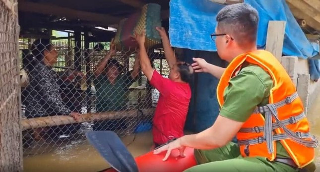 Lực lượng Công an, dân quân địa phương hỗ trợ dân sơ tán người đồ đạc ra khỏi vùng lũ.