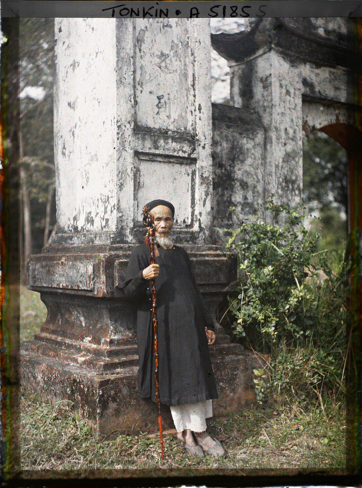 Vị hương chức đứng bên cánh cổng tam quan đồ sộ ở một ngôi làng.