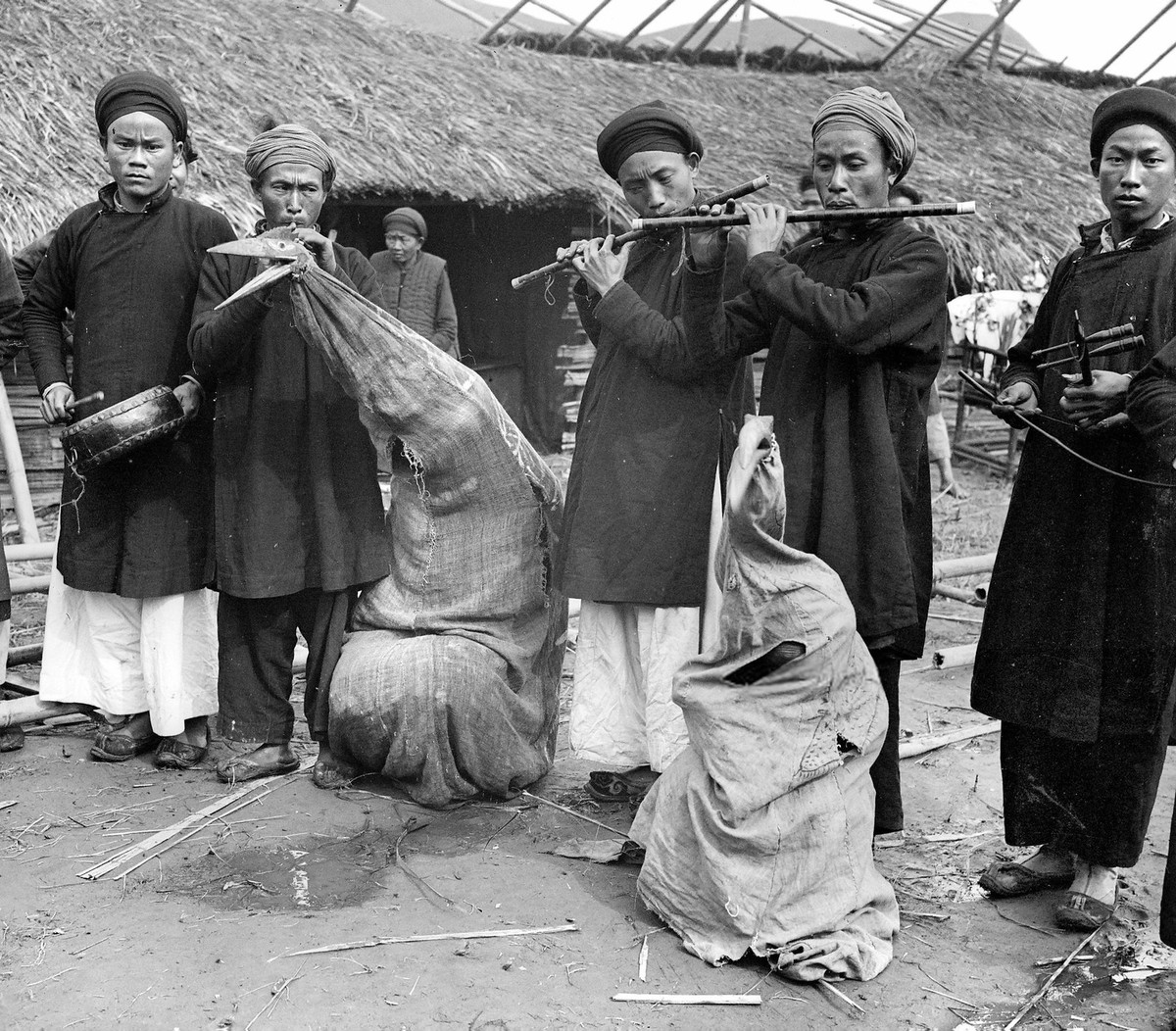 Các nhạc công đánh trống, thổi kèn, kéo đàn trong một đám tang ở Bảo Lạc, Cao Bằng năm 1902. Hai người hóa trang thành chim thần theo phong tục địa phương. Ảnh: LL/Roger Viollet via Getty Images.