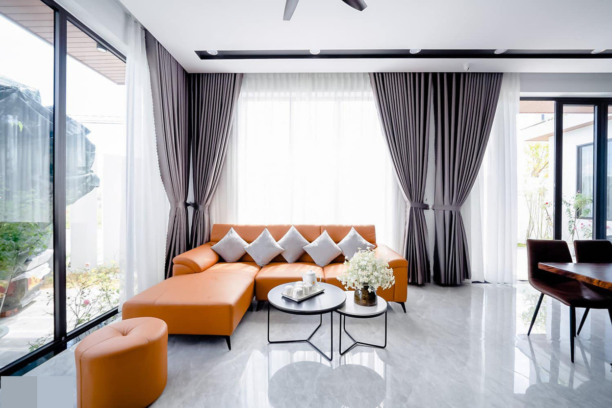 Màu cam của sofa phối với màu xám của rèm cửa, sàn nhà tạo nên sự tương phản rõ nét.