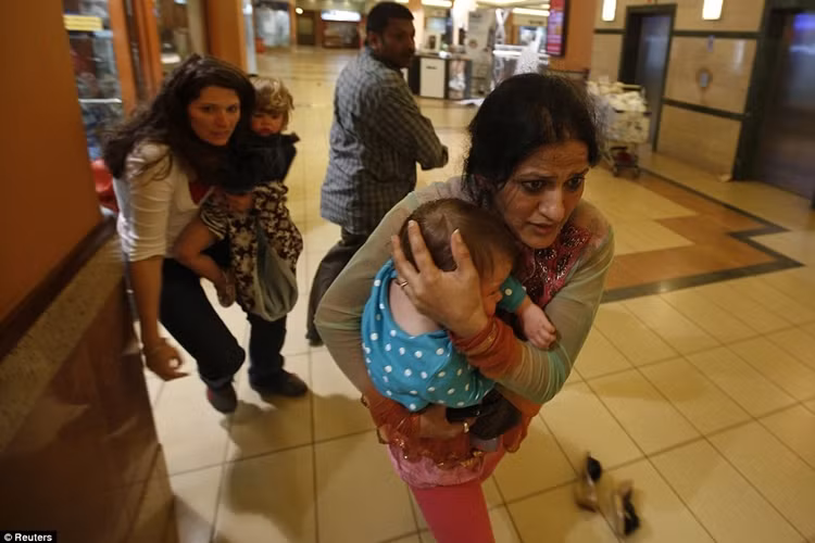 Những người mẹ bồng con hối hả rời trung tâm thương mại.