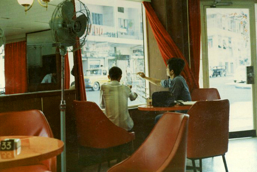 Từ các bàn trà trong vũ trường nhìn ra phố, 1972. Hai người thợ đang vẽ trang trí Giáng sinh trên cửa kính. Ảnh: Chip Seiple Collection.