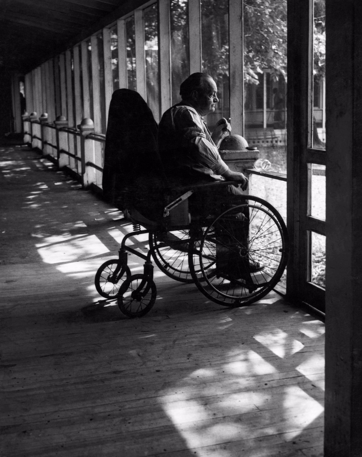 Một người đàn ông ngồi xe lăn nhìn cảnh vật ngoài sân.