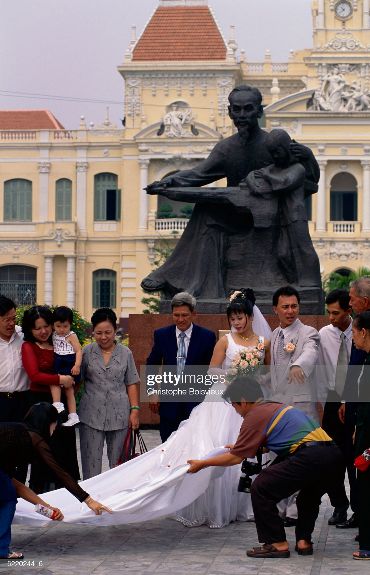 Một cặp đôi chụp ảnh cưới tại tượng đài Bác Hồ với thiếu nhi, phía trước Tòa nhà UBND TP. HCM.