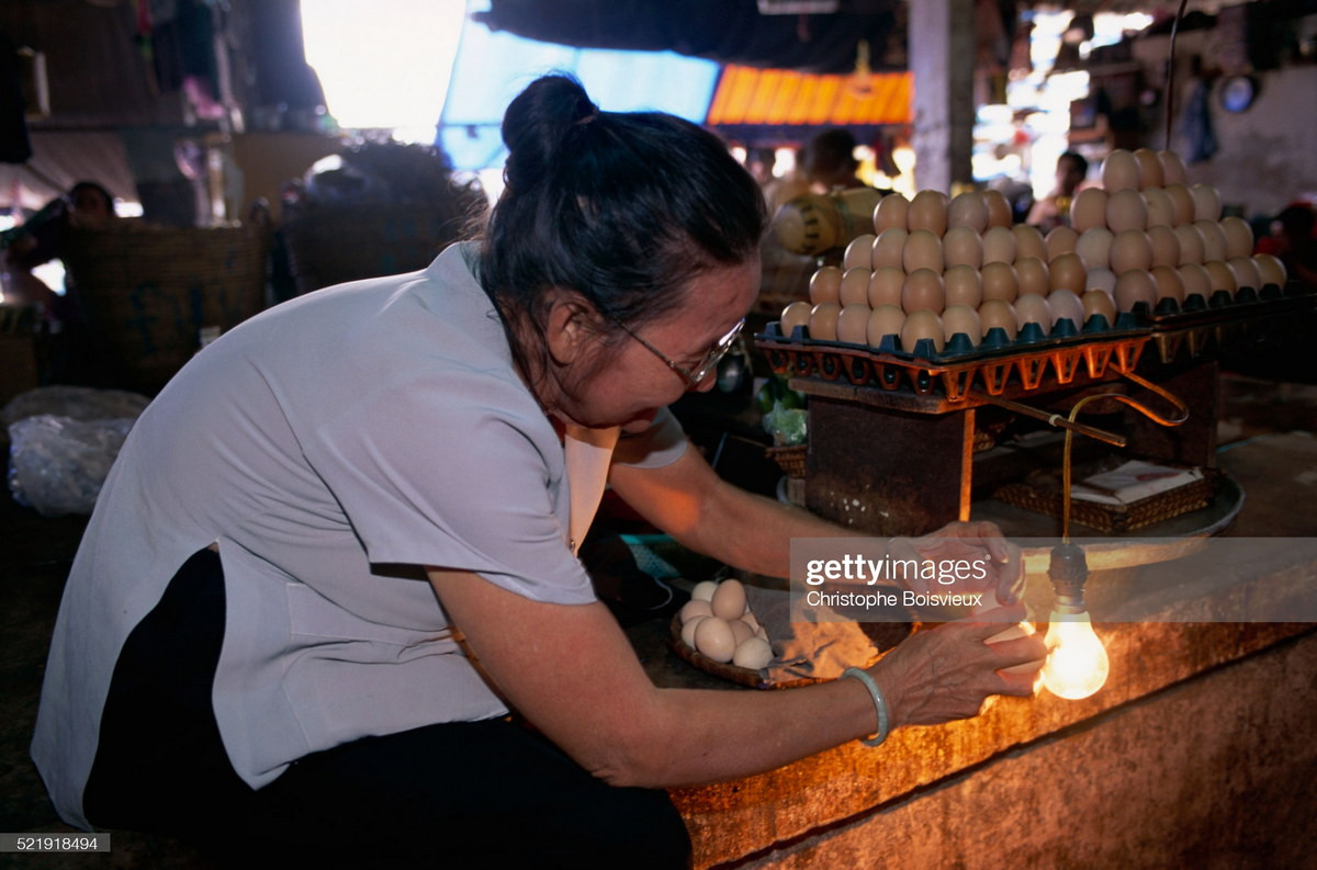 Cụ bà soi trứng gà tại chợ Cầu Ông Lãnh.