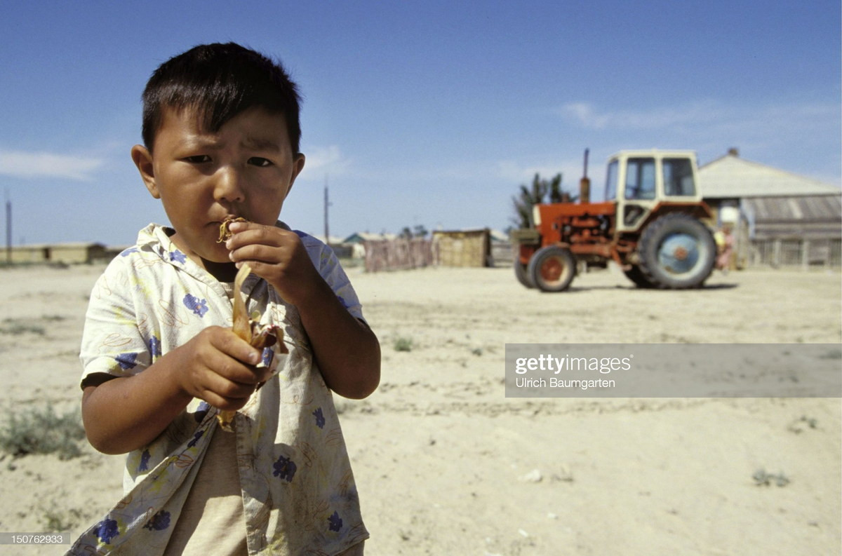 Một cậu bé đứng ở sân nông trại, nơi từng là mặt biển Aral.