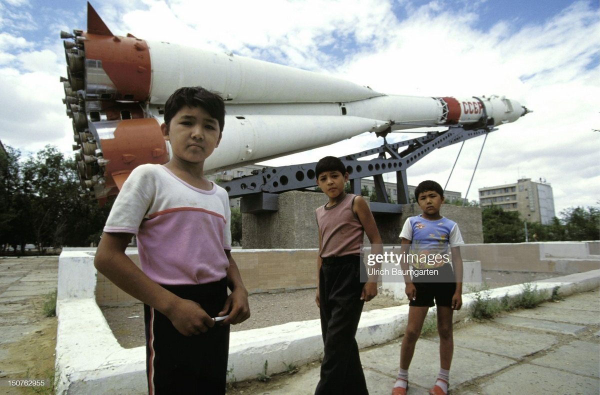 Những đứa trẻ đứng trước đài kỷ niệm tên lửa Soyuz của Liên Xô. Kazakhstan là nơi có sân bay vũ trụ Baykonur, sân bay vũ trụ đầu tiên và lớn nhất trên thế giới do Liên Xô xây dựng.