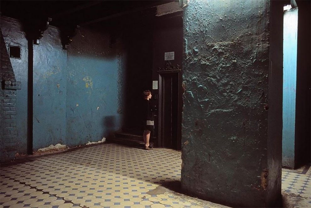 Người phụ nữ chờ thang máy tại một toà nhà cũ kỹ.