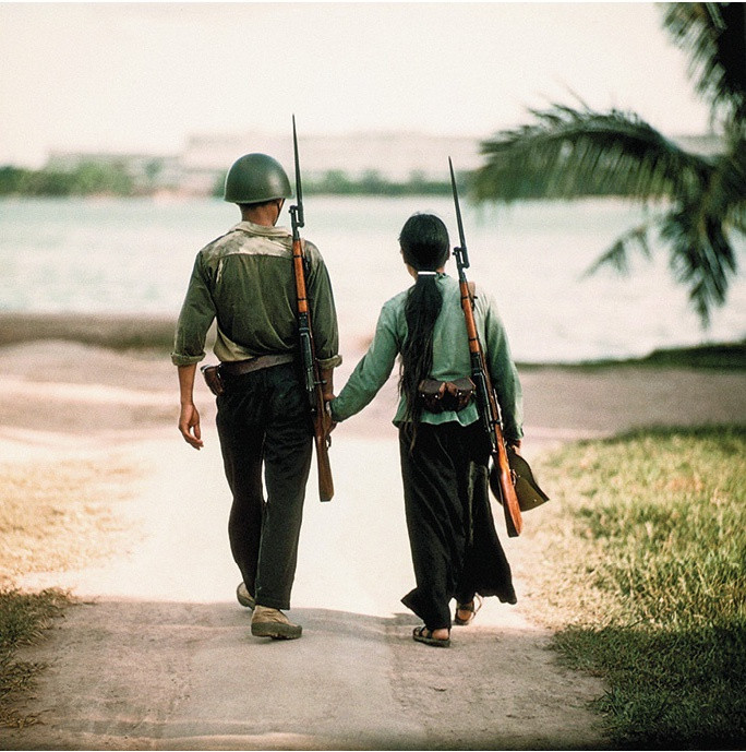 Hình ảnh đôi nam nữ dân quân được chụp tại Hà Nội năm 1968. Tác giả chia sẻ rằng ông đã chụp rất nhiều ảnh phía trước mặt, cũng như sau lưng của đôi dân quân trên nhưng không cái nào khiến ông rung động như bức đầu tiên. Vì thế, ông đã chọn nó để tham gia nhiều cuộc triển lãm trên thế giới.