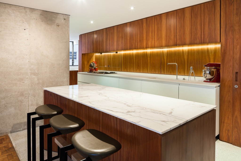 Khu bếp có một mặt bàn đá dài 4,5 m và tủ bằng kim loại với màu sắc tương phản.