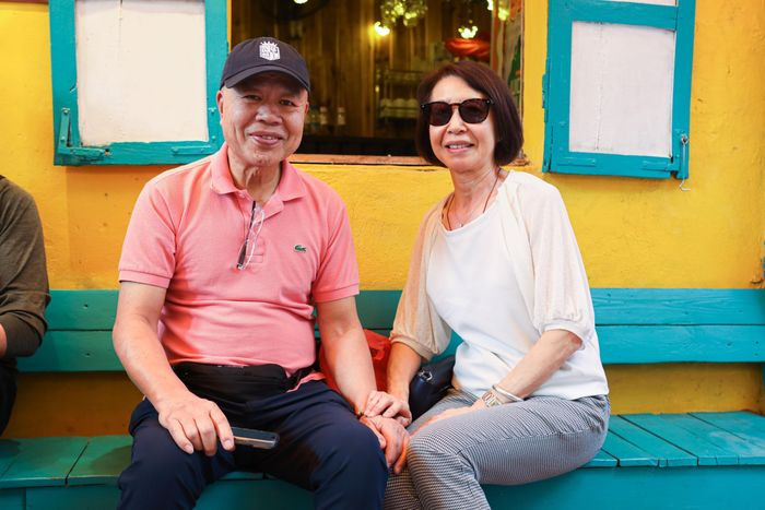 Bà Nina (ngoài 60 tuổi, bên phải), du khách người Trung Quốc, cùng gia đình đi du lịch Việt Nam và được hướng dẫn viên gợi ý đến phố cà phê đường tàu. Người phụ nữ cho biết cảm thấy kinh ngạc khi chứng kiến cảnh đoàn tàu di chuyển ngay trước mặt. "Nếu ở nước ngoài sẽ không cho ngồi như thế này vì rất nguy hiểm. Tuy nhiên, đây là một trải nghiệm thú vị có một không hai", bà nói với Tri Thức - Znews.