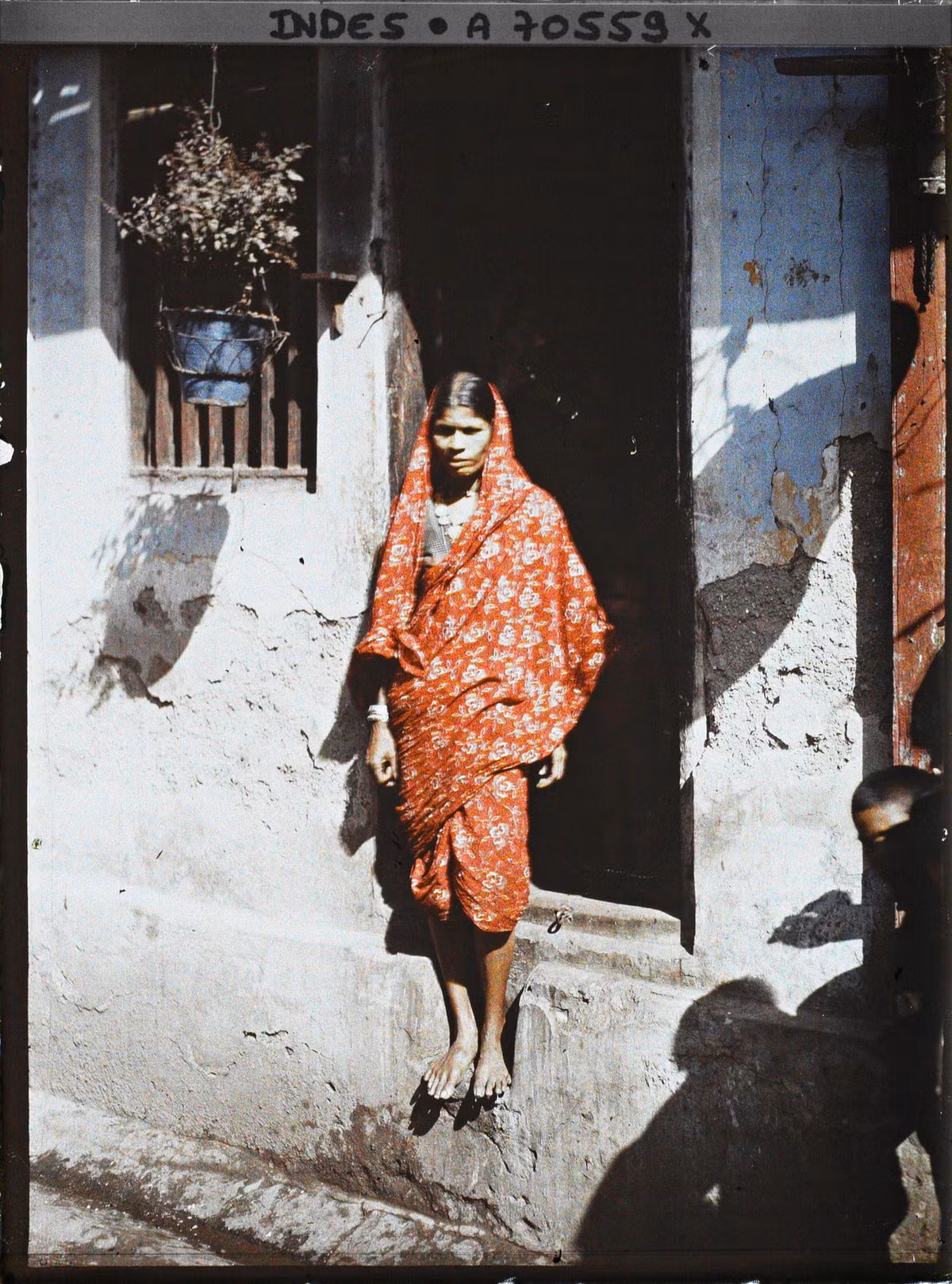 Người phụ nữ Ấn Độ mặc sari đứng bên cửa nhà.