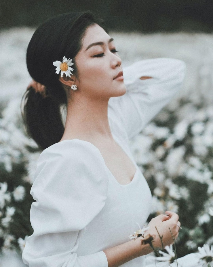 Ở đây, cô chọn một chiếc đầm trắng cổ vuông màu trắng để chụp cùng hoa cúc họa mi.