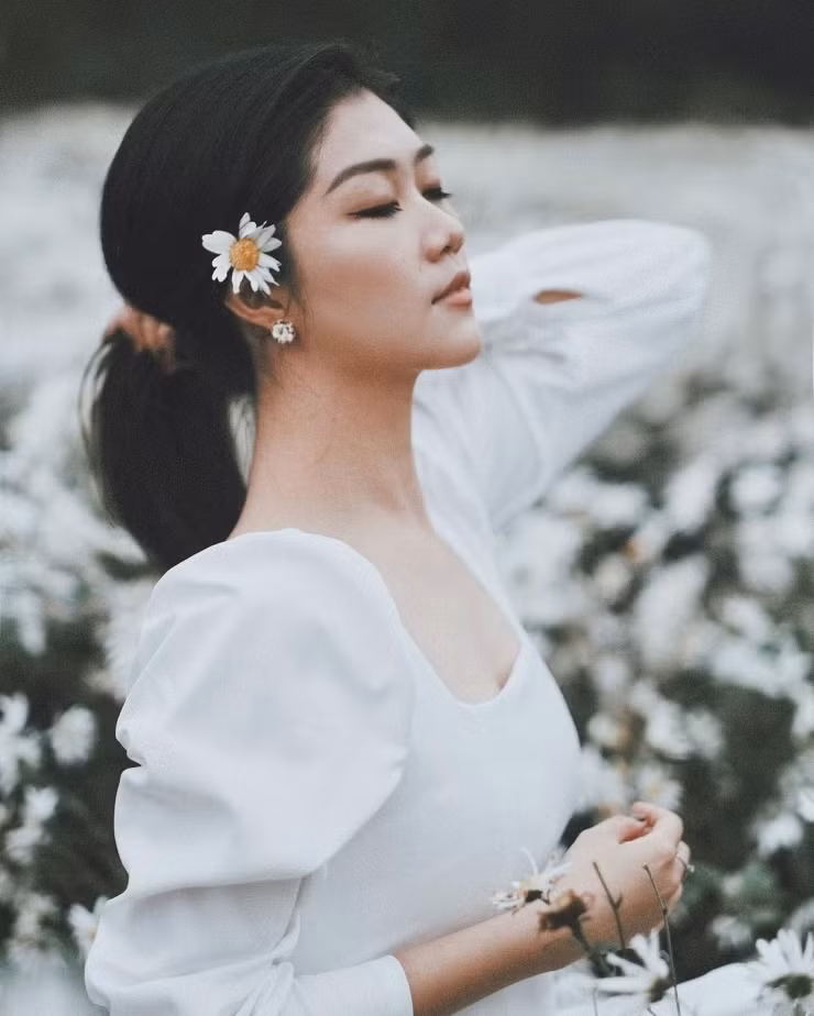 Ở đây, cô chọn một chiếc đầm trắng cổ vuông màu trắng để chụp cùng hoa cúc họa mi.