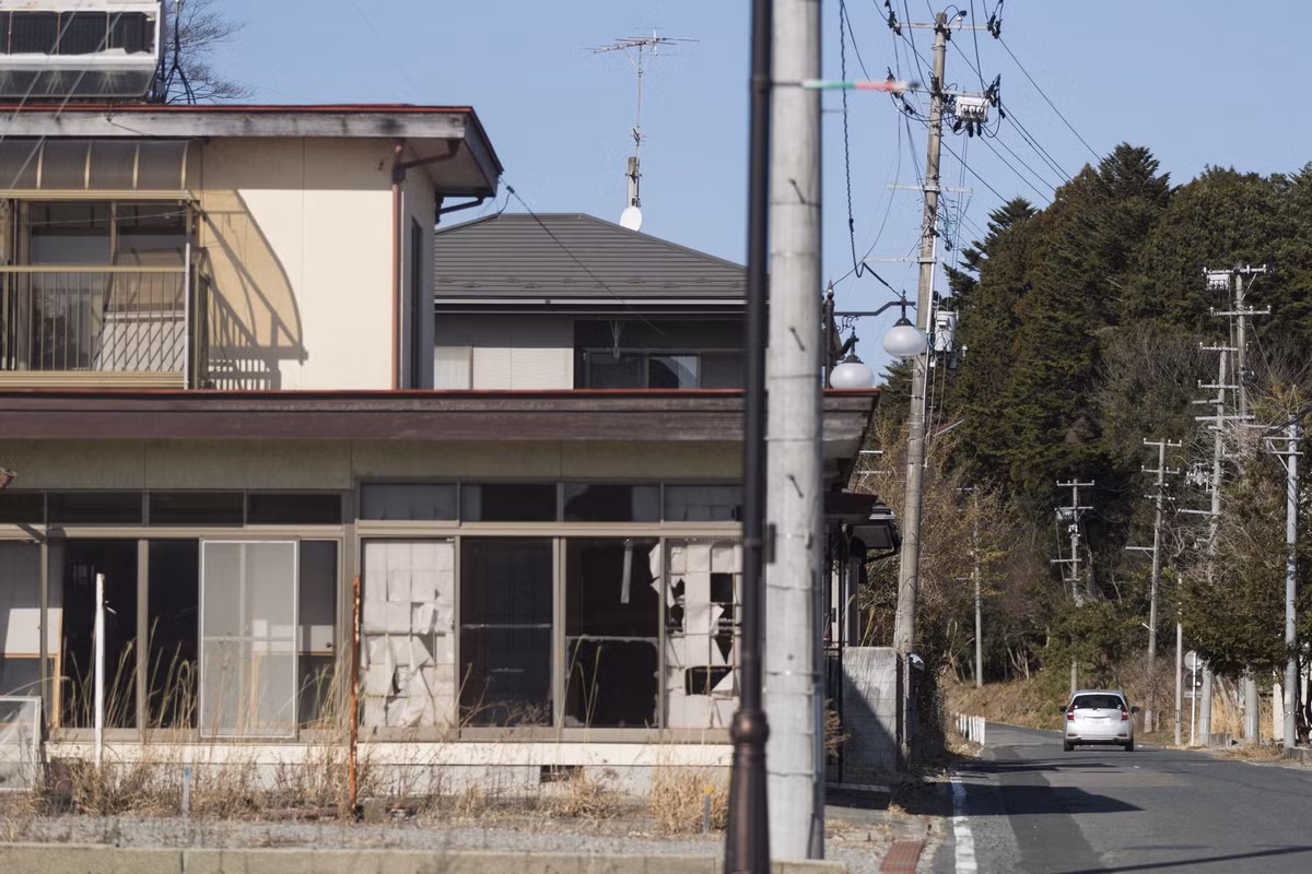 Một phương tiện tuần tra cộng đồng di chuyển giữa những ngôi nhà hoang ở thị trấn Futaba.