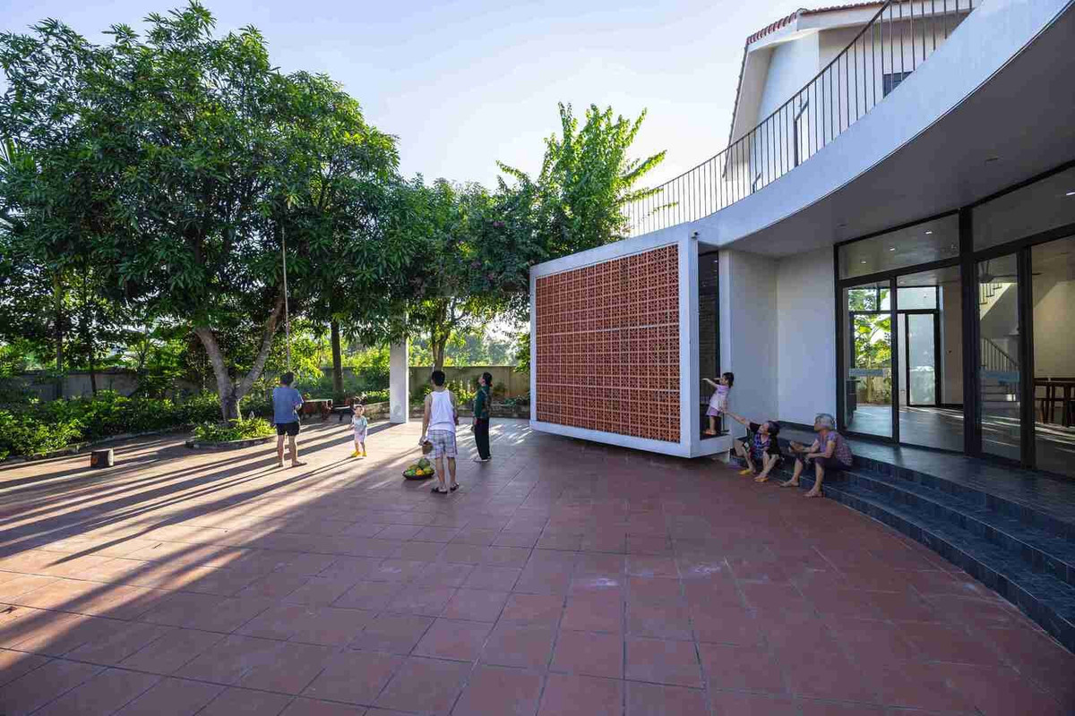 Sân vườn sử dụng gạch men đỏ, trần nhà tầng hai được làm bằng tre, tạo nên bầu không khí hiện đại nhưng thân thiện và ấm cúng cho ngôi nhà.