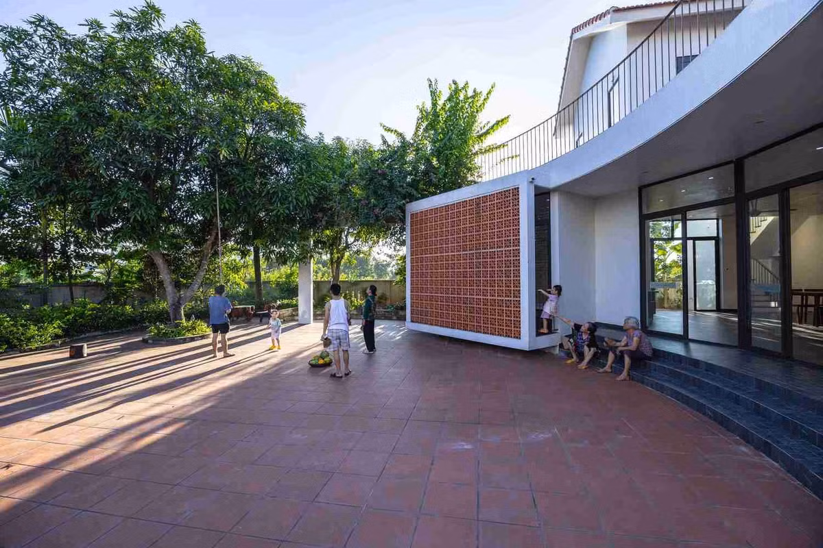 Sân vườn sử dụng gạch men đỏ, trần nhà tầng hai được làm bằng tre, tạo nên bầu không khí hiện đại nhưng thân thiện và ấm cúng cho ngôi nhà.