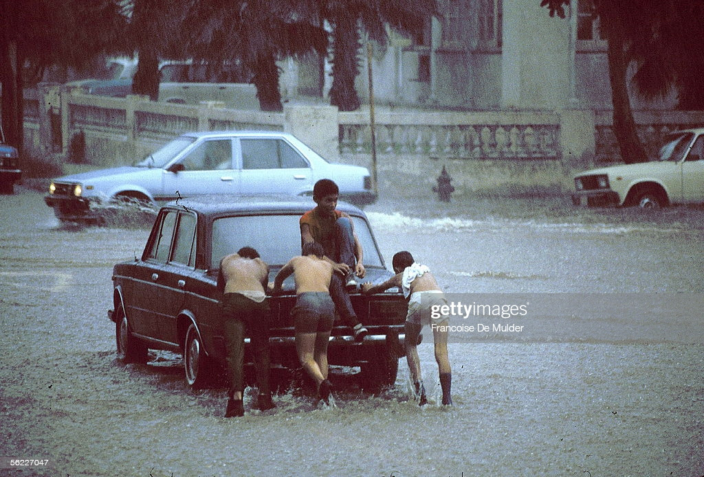Ba thanh niên đẩy chiếc xe hơi trên đường phố Havana ngập nước sau cơn bão nhiệt đới.