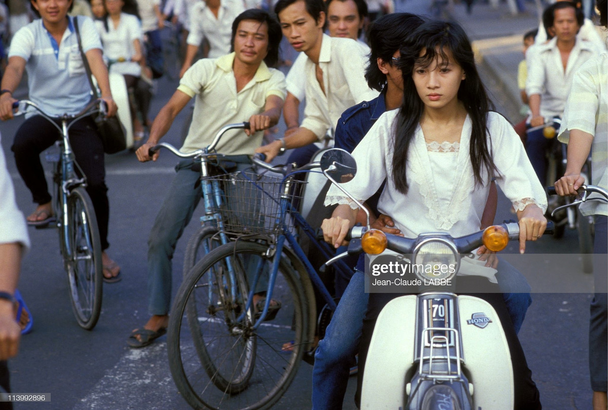 Cô gái trẻ chở một nam thanh niên trên xe Honda Cub ở Sài Gòn.