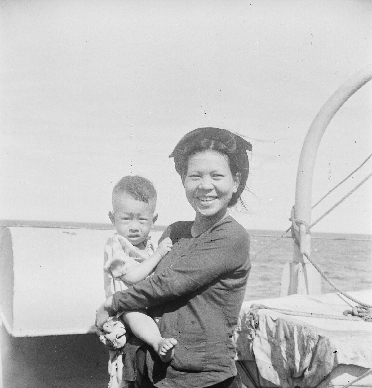 Bà mẹ trẻ và đứa con đứng trên một con thuyền.